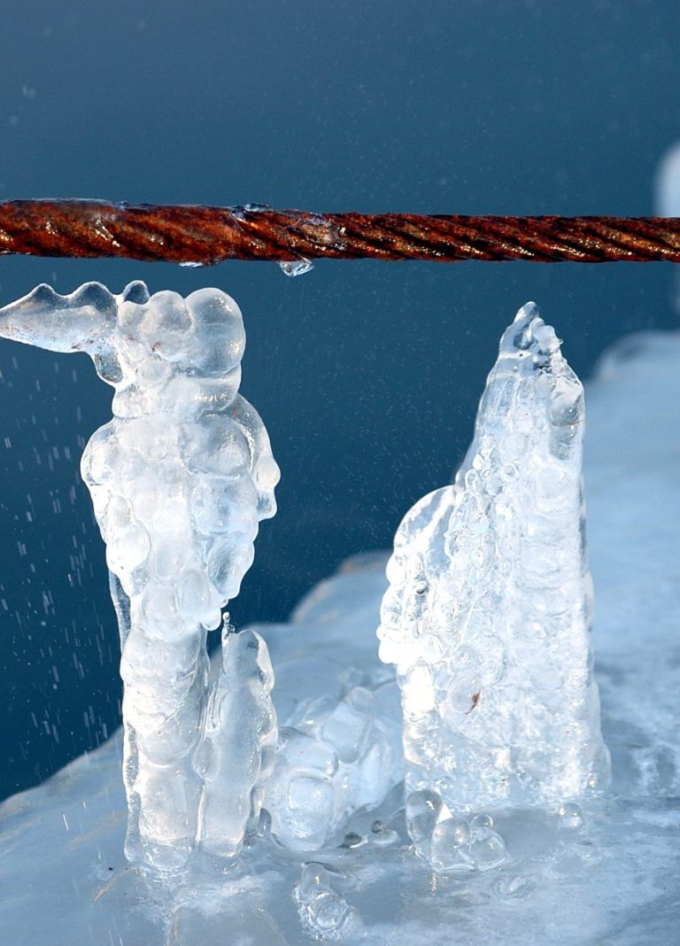 Zwei gefrorene Figuren, verbunden nach unten mit einer Eisplatte, stehen unter einem dicken Seil; das Seil ist Symbol für die selbstgewählte Begrenzung im Denken, was schließlich zu einer Erstarrung im Körper und Fixierung am Ort führt.